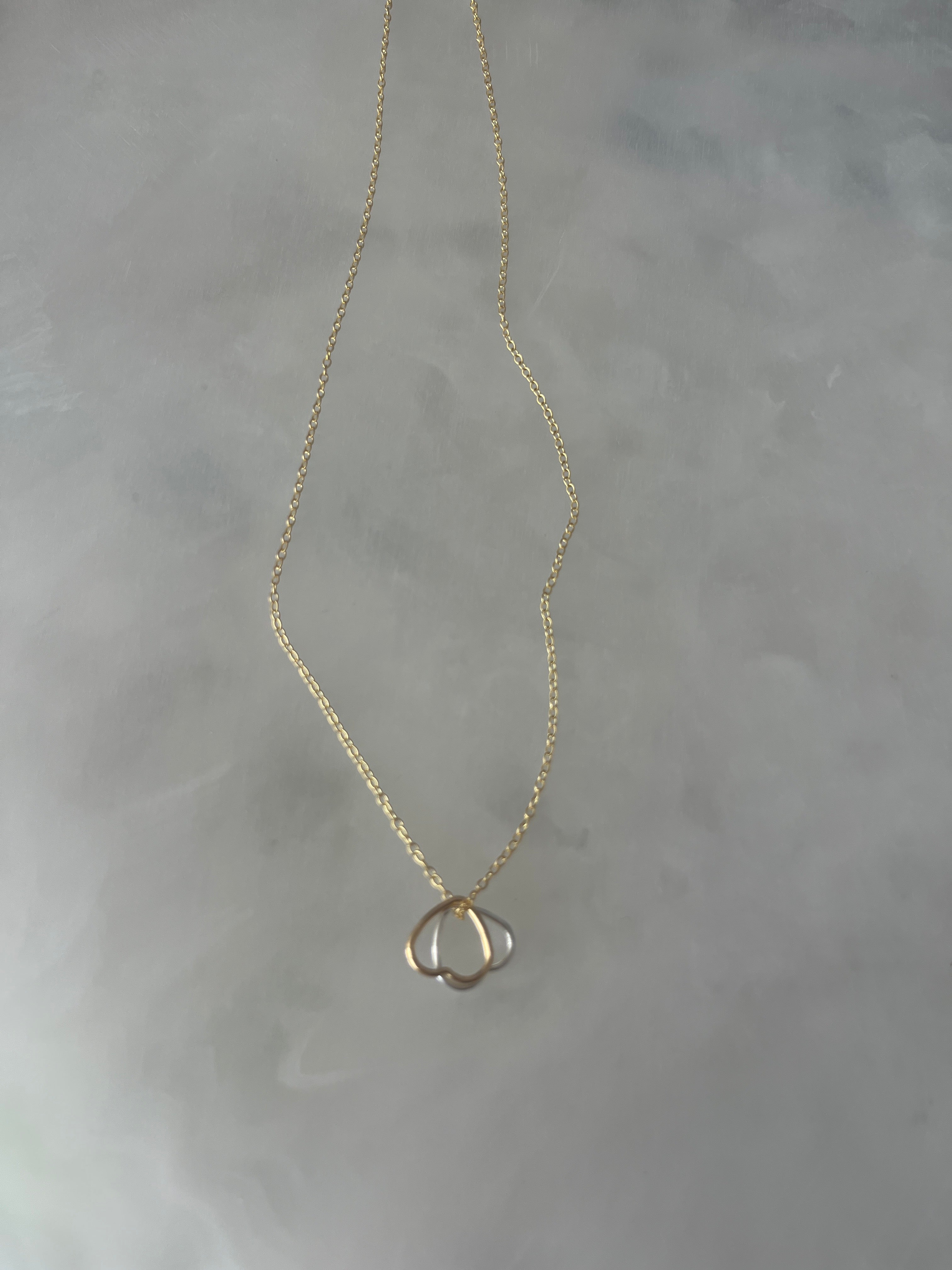Two open hearts, gold and silver together on gold chain necklace.